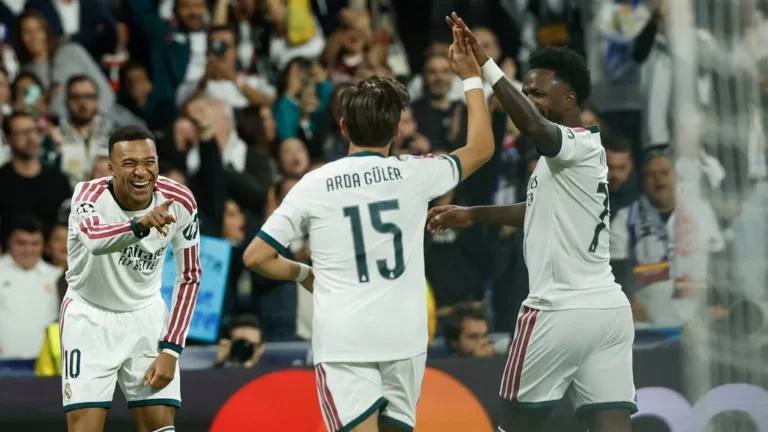 Real Madrid's Turkish midfielder Arda Guler (center) celebrates his team's second goal with teammates French forward Kylian Mbappe (left) and Brazilian forward Vinicius Junior, during the UEFA Champions League first leg match day 3 between Real Madrid CF and RB Leipzig at the Santiago Bernabeu Stadium, Madrid, on October 21, 2026. Oscar DEL POZO / AFP